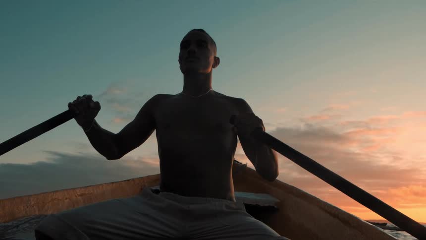 A man rows his boat at dusk