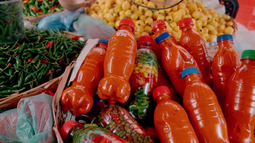 A display of vegetables and vegetable juices sits in a market in baskets