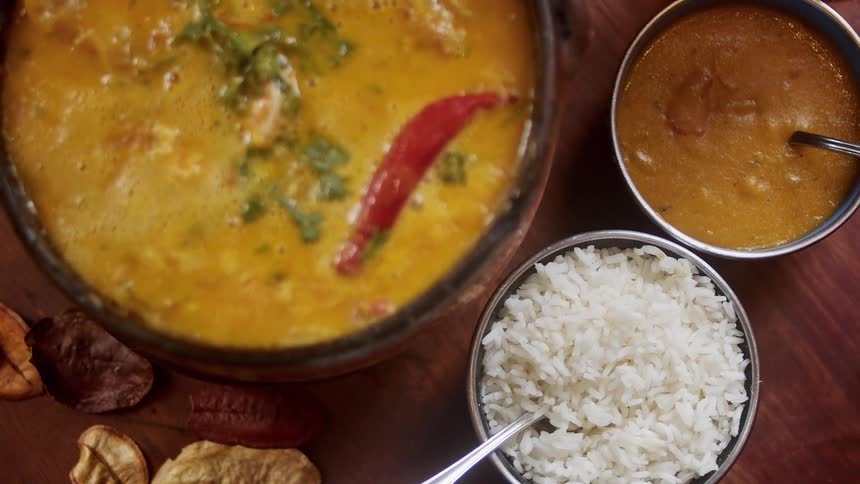 Rice and soup are served in separate bowls placed on top of a wooden table