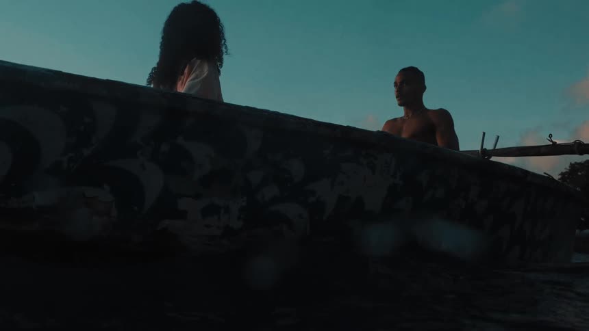 Shirtless man steering a canoe with a woman