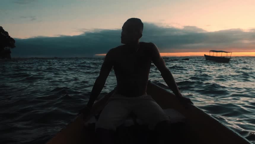 The man looks around at the water as he sits in the rowboat