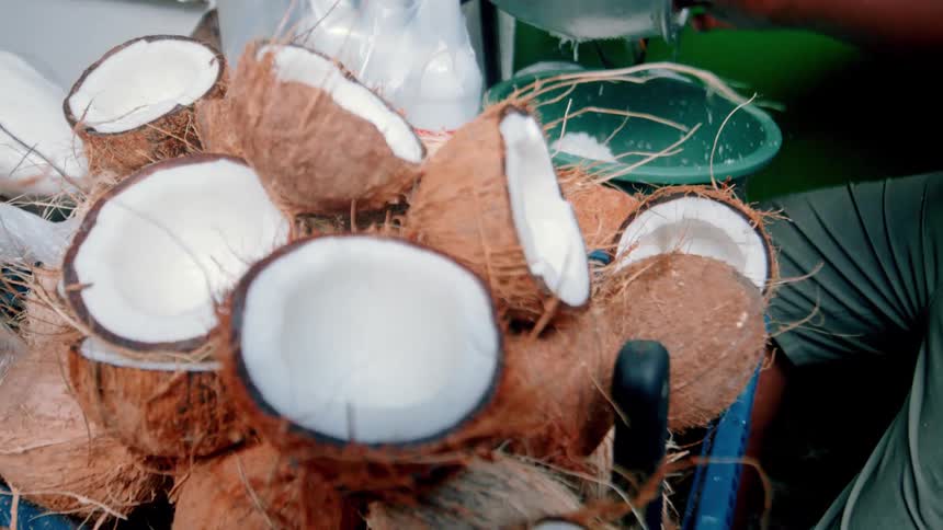 A man is shaving coconuts outside