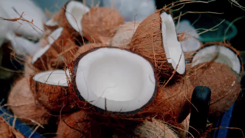 A series of broken coconut pieces are stacked in a bucket