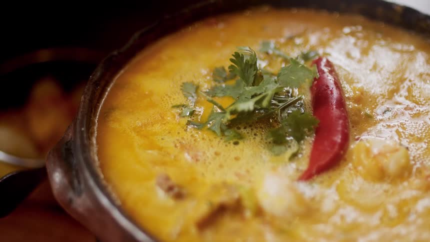 A closeup shot of a vibrant freshly prepared dish garnished with coriander leaves and a red chili