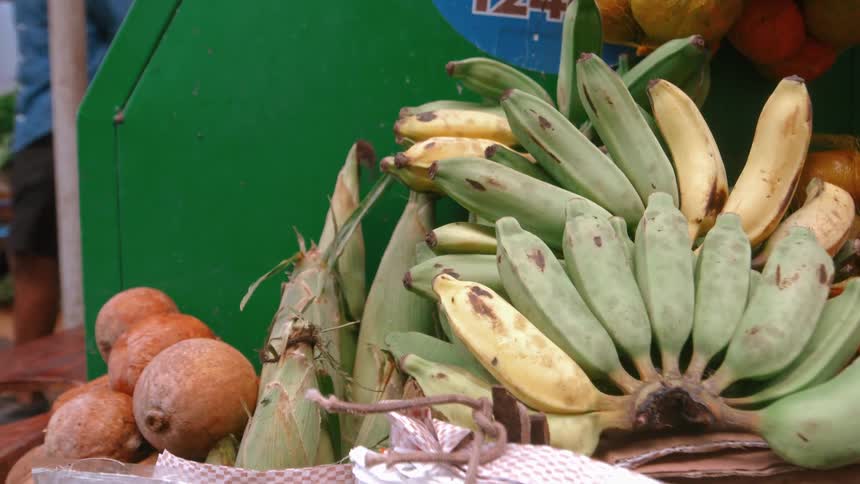 A fruit stand in the market displays bananas along with a variety of other fruits