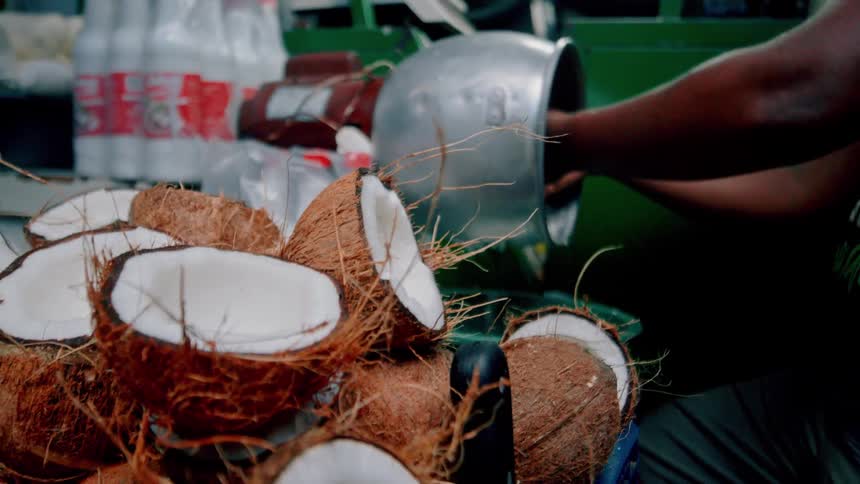 A vendor grates fresh coconuts at a street stall
