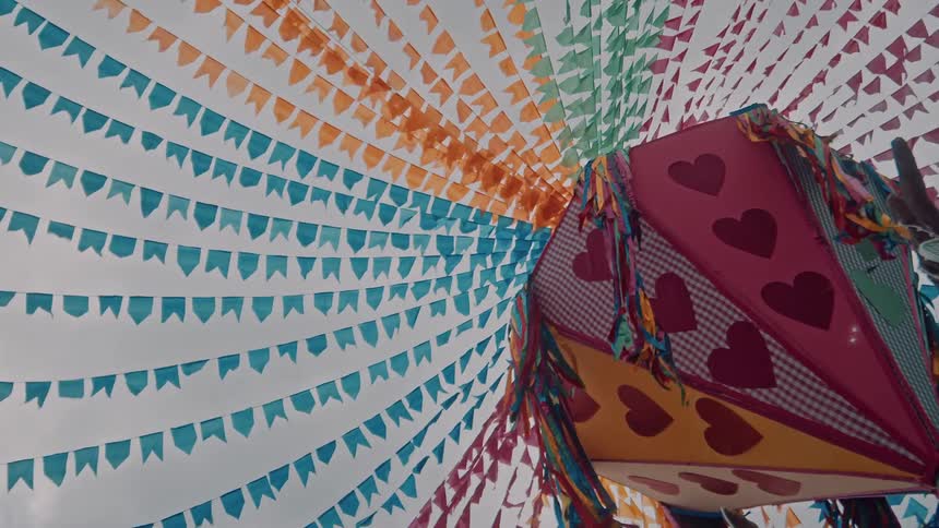 Colorful pennant flags radiate from a festive heartcovered lantern creating a decorative canopy for a celebration