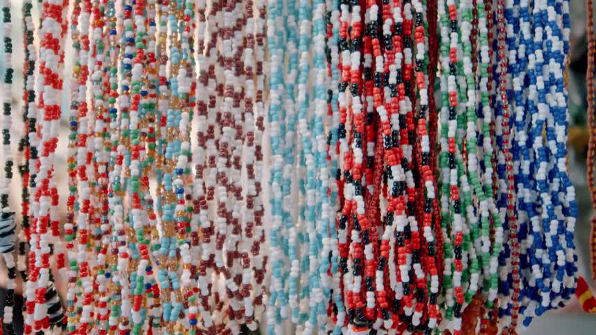 Colorful beaded handcrafted necklaces displayed outdoors swaying in the breeze