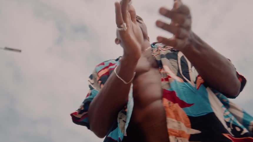 The man claps his hands under a cloudy sky