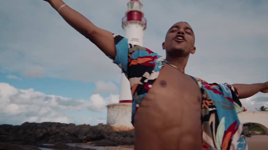 A man stands with his arms up on a beach