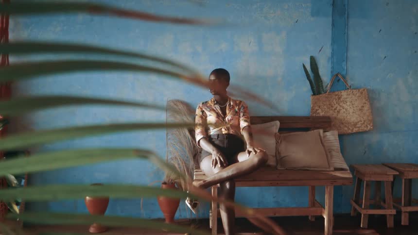 Black african woman poses while sitting on a wooden chair indoors