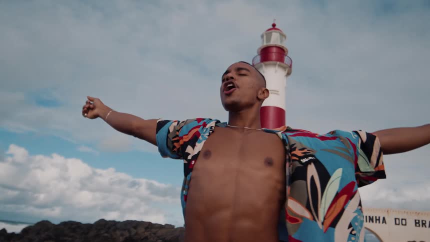 The man lifts his arms by the light house