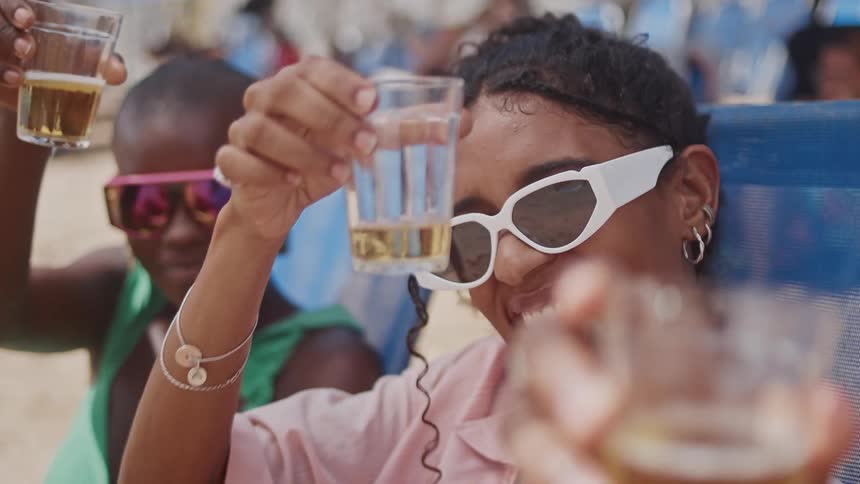 People toast with drinks on a sunny beach celebrating together