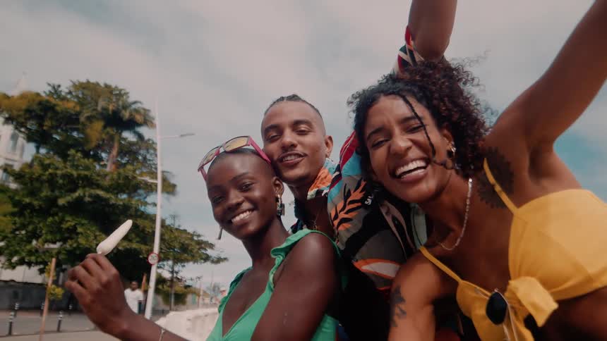 A man relaxes with two women one of whom is holding a popsicle as they all smile and enjoy each others company