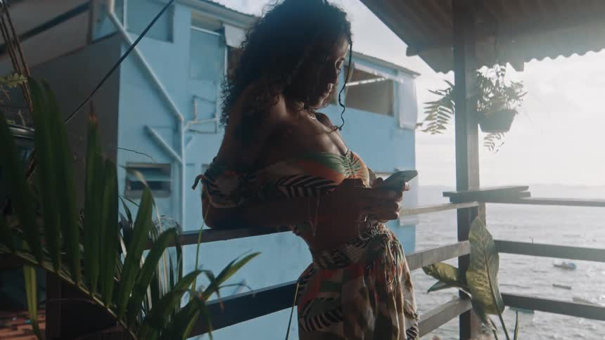 A woman is texting on the balcony by the water