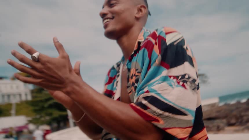 A happy man near the beach clapping his hands and smiling