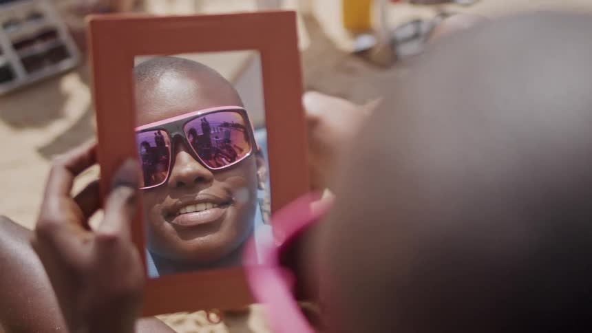 The woman smiles while looking at a mirror