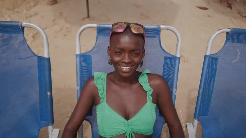 A woman is sitting on the beach smiling