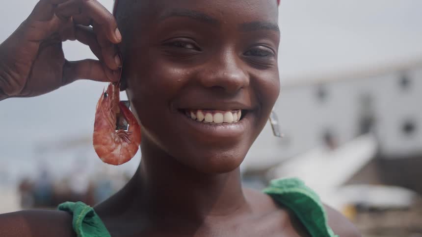 Smiling woman playfully holds a shrimp as an earring