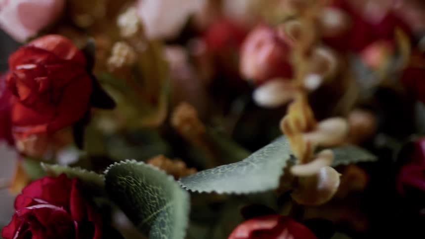 A floral arrangement contains several red roses and some lighter ones too