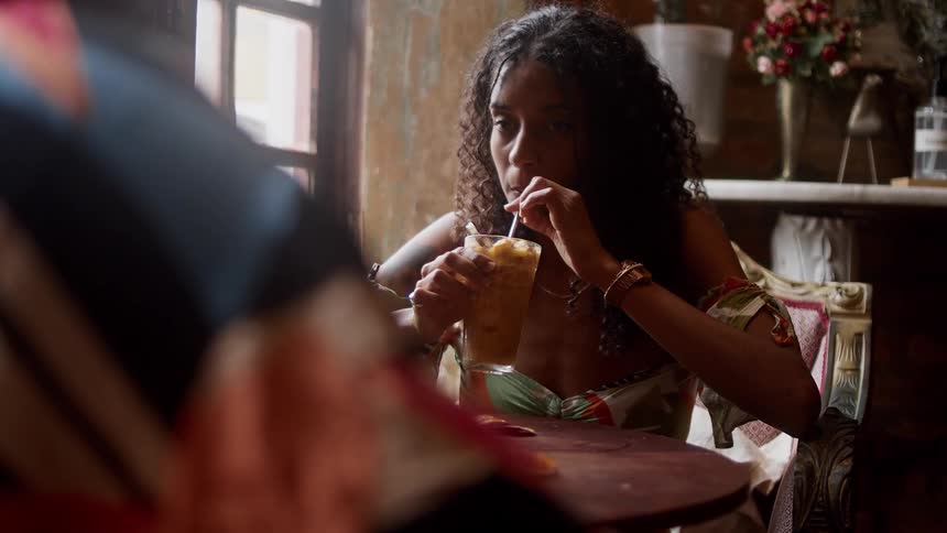 Woman sips a smoothie while chatting on a date at a cafe
