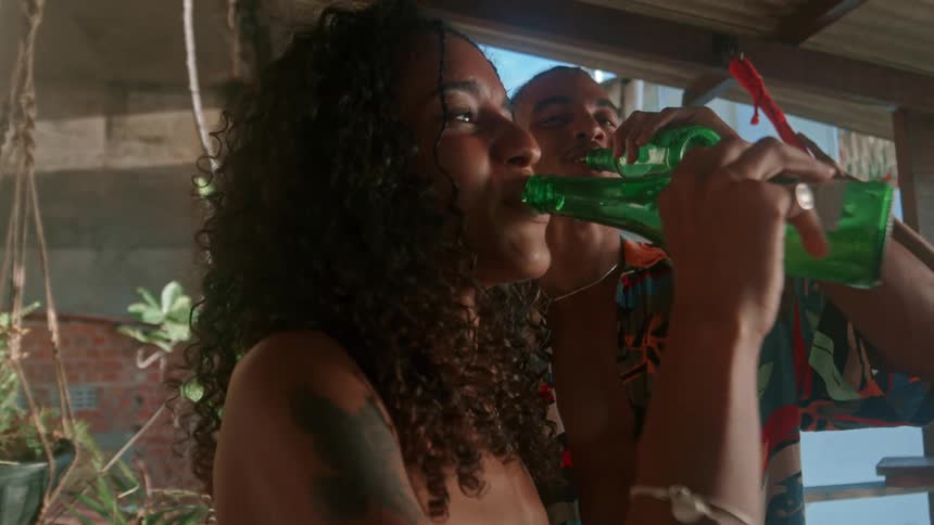 Man and woman drinks and smiles while standing under a shade at daytime