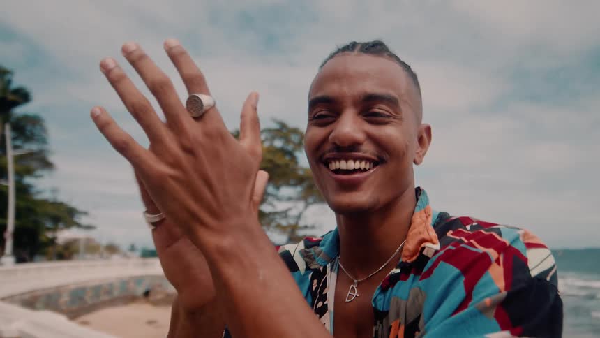 A man is clapping his hands and smiling on the beach