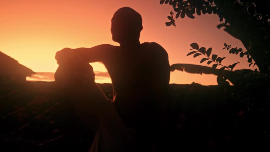 A man sits in the dark as the sun sets