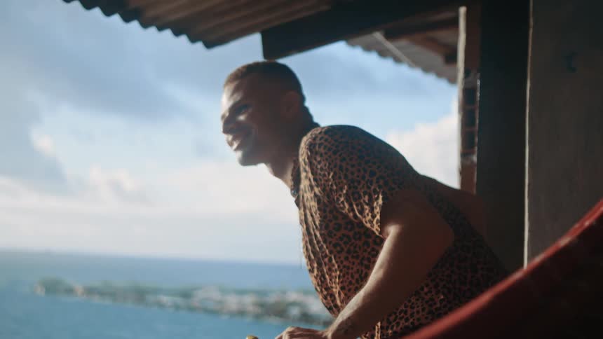 A man leans over the terrace and waves