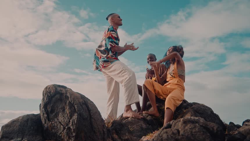 Group of black friends clap and dance on top a rock during daytime