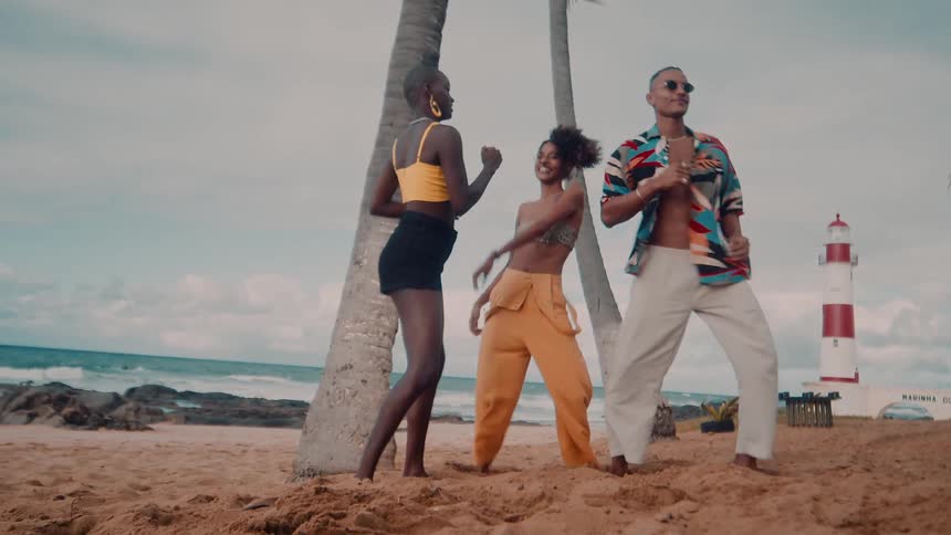 Three people happily dancing near a beach