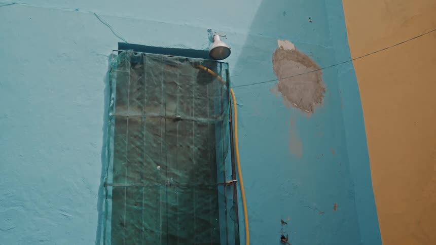 Metal frame with mesh screen used as a door allows a hose to pass through