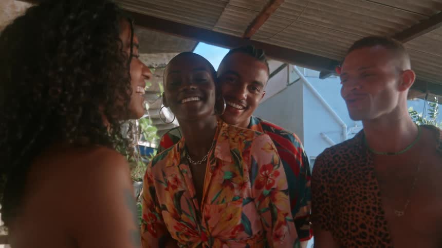 Four friends dance slowly and smile together in a sunlit outdoor setting