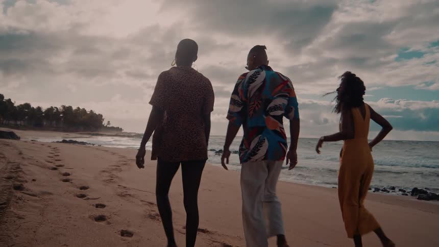 Three friends joyfully walk along a scenic beach laughing together