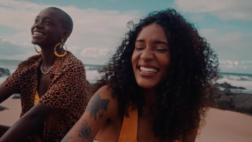 Two black women smiling at the beach shore