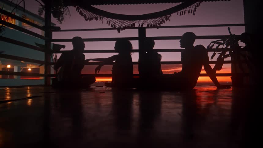 A group of people sits together on the floor of a balcony