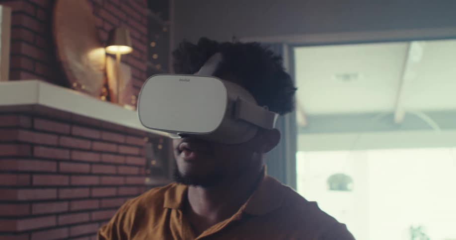 Man uses a virtual reality headset while moving around in his living room during the daytime