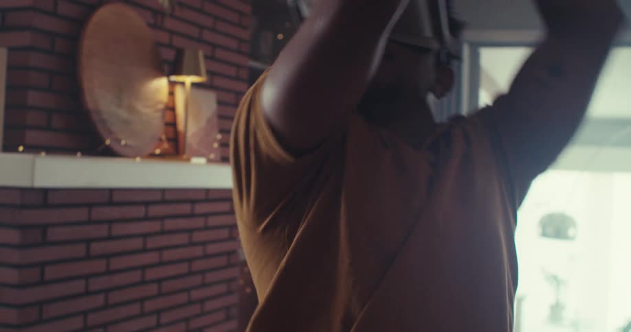 A man immersed in virtual reality swings a controller while wearing a vr headset