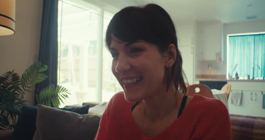 Woman smiles while playing a video game in her living room during the daytime