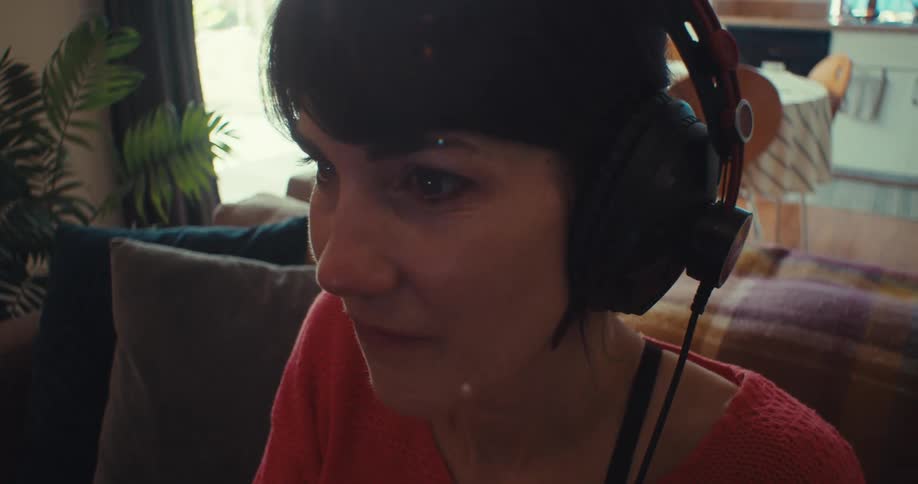 A woman sitting on the couch at home playing video games