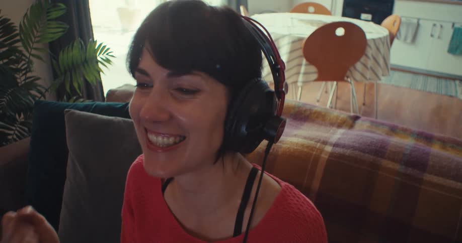 Woman wearing headphones while playing a video game celebrates