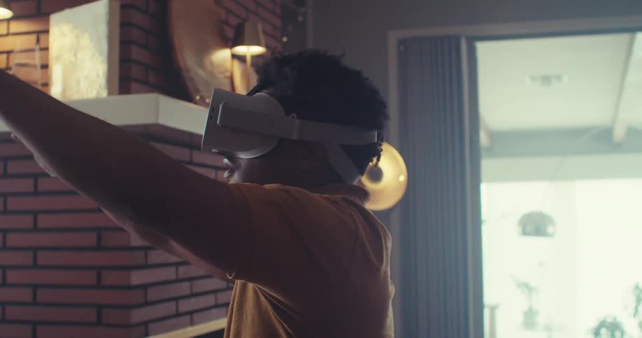 The man has his arms stretched out as he uses a virtual reality headset