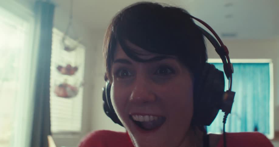 The woman smiles and talks while playing video games
