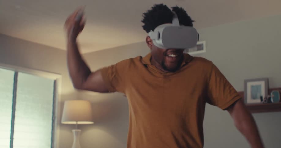 The man swings his arm while wearing a virtual reality headset
