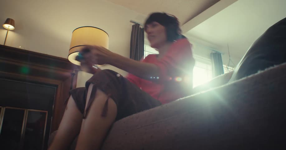 Woman smiles while playing a video game with headphones on