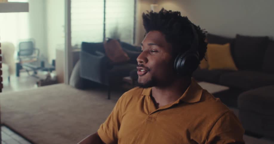 The man sits back and puts on headphones