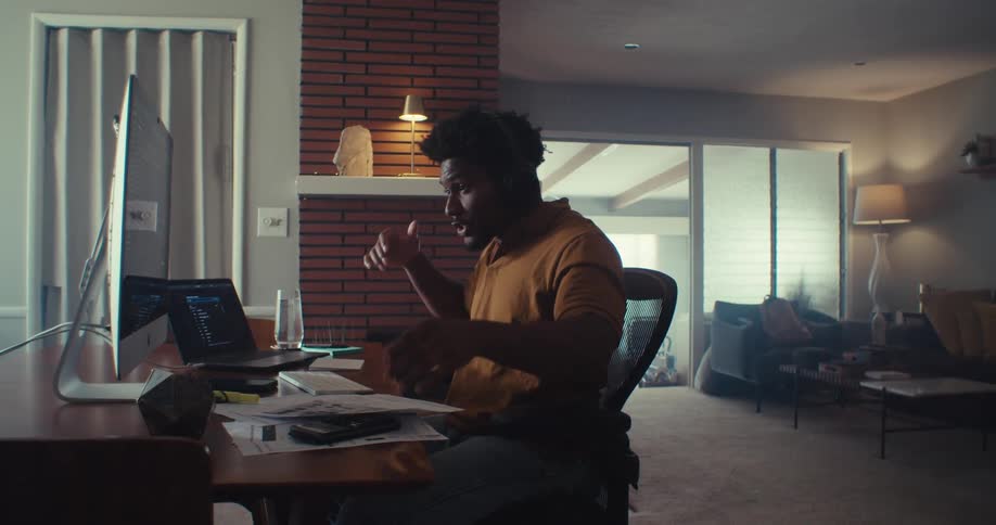 The man leans back in his chair at the desk