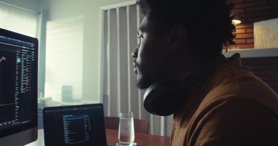 A man at the dining table in his home looking at a binary options chart on the computer monitor