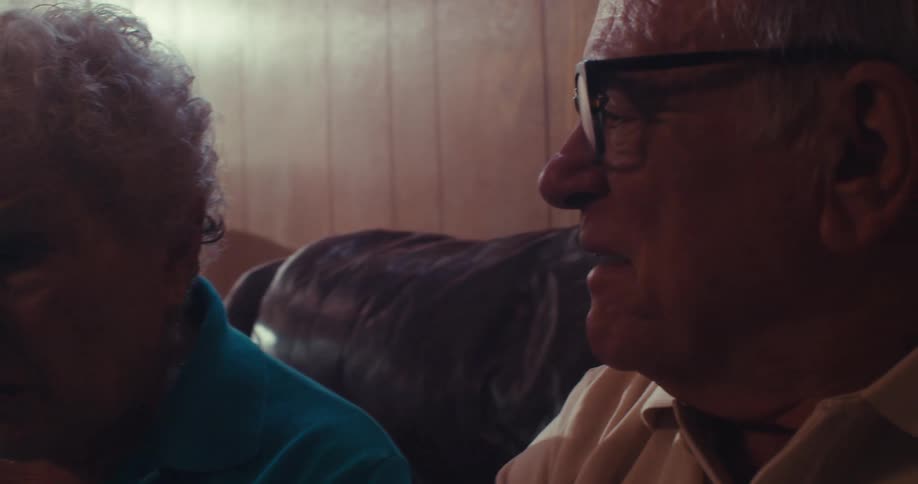 Elderly couple sitting in their living room reviews a financial graph during the daytime