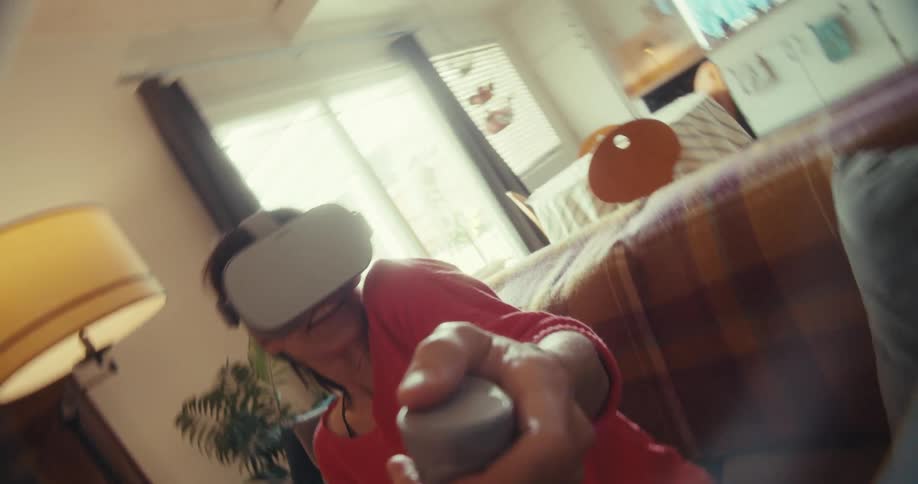 Person with vr headset points controller toward camera on a cozy couch